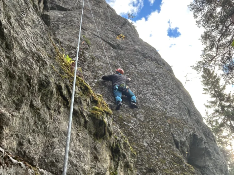 En man hänger på en klippvägg och klättrar uppåt.